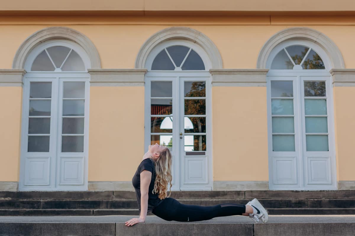 Lara Kölzow dehnt sich in der Kobra-Position auf den Stufen vor einem historischen Gebäude