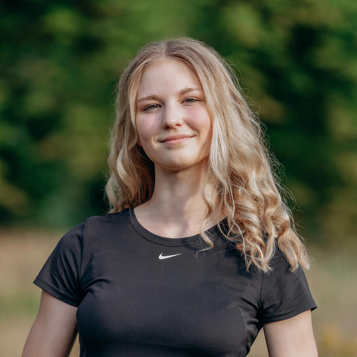 Porträt von Lara Kölzow, Personal Trainerin aus Hannover, lächelnd im Park